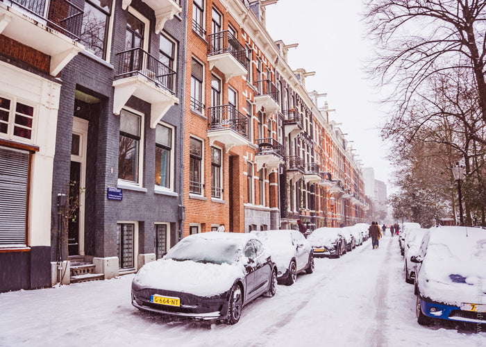 snow in Amsterdam, Amsterdam winter street, snowy Amsterdam canal houses, winter in Amsterdam Netherlands, Amsterdam snow scene cars, Dutch city winter atmosphere, snow covered street Amsterdam, Amsterdam architecture winter, cozy winter street Europe, Am